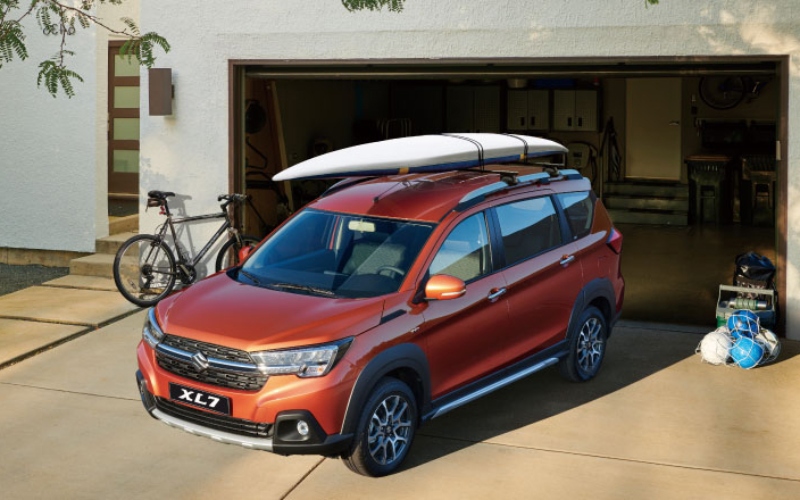 Suzuki XL7 Smart Hybrid naranja con tabla de surf y equipaje de viaje
